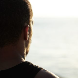 back shot handsome dark skinned young athlete enjoying sunny summer days ocean contemplating sunrise